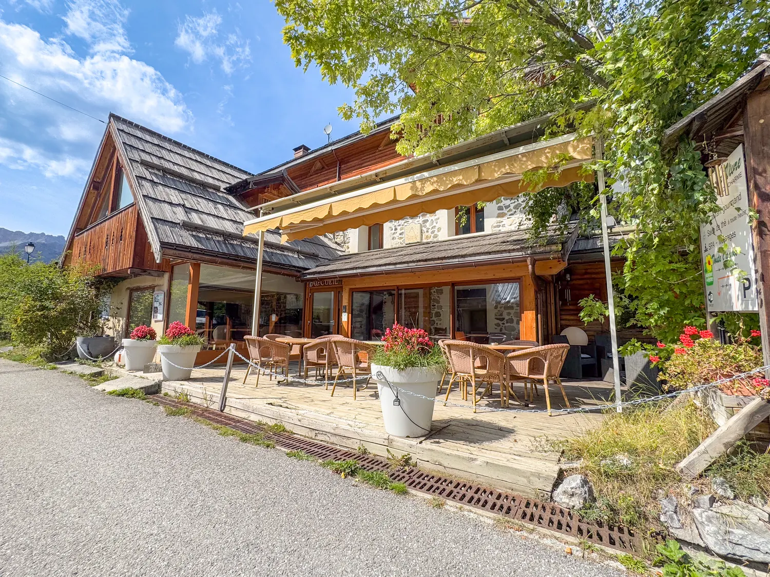 Chalet principal : façade bois et pierre, terrasse et géraniums