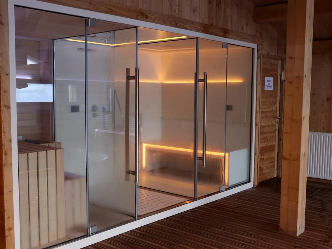 Sauna vitré de l'espace bien-être, bancs de bois et lumière tamisée